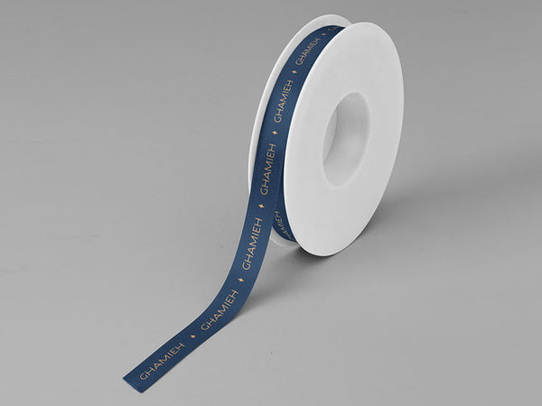 Custom navy ribbon roll printed with gold logo wordmark and star icons, premium packaging accent.