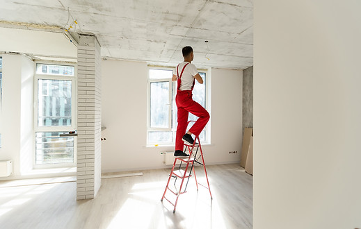 Electrician mounts halogen lamp in ceili