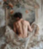 Man reclining against a decorated wall, partially draped in a white cloth, conveying a modern and artistic approach to branding and design.