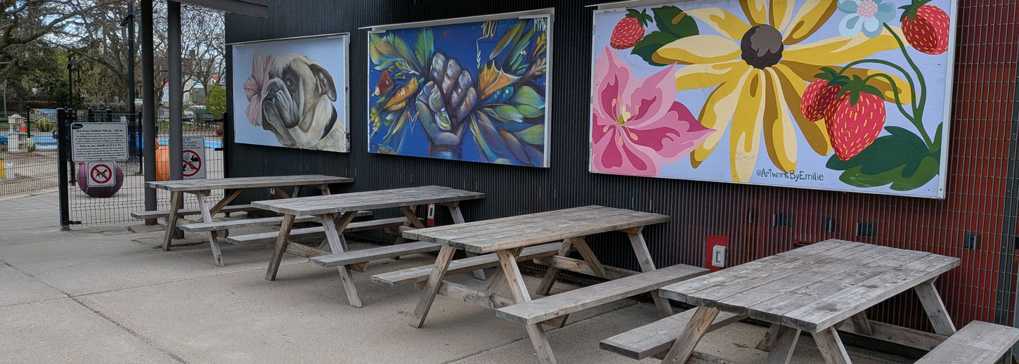 Picknic tables with art in the background.