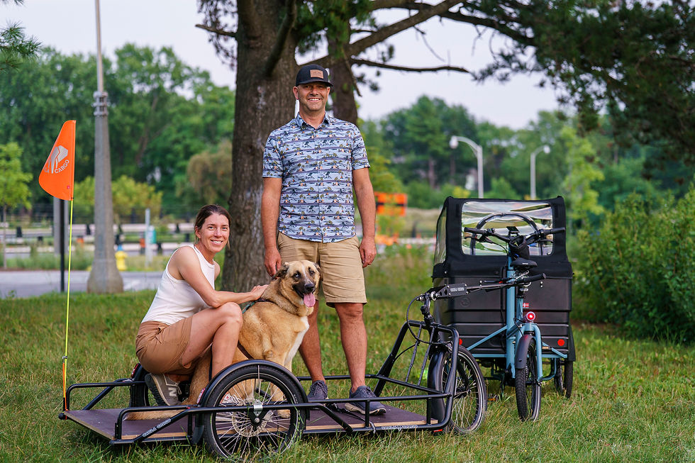 Deux personnes (et un chiot!) debout sur la remorque d'un vélo cargo à la plage Westboro d'Ottawa.