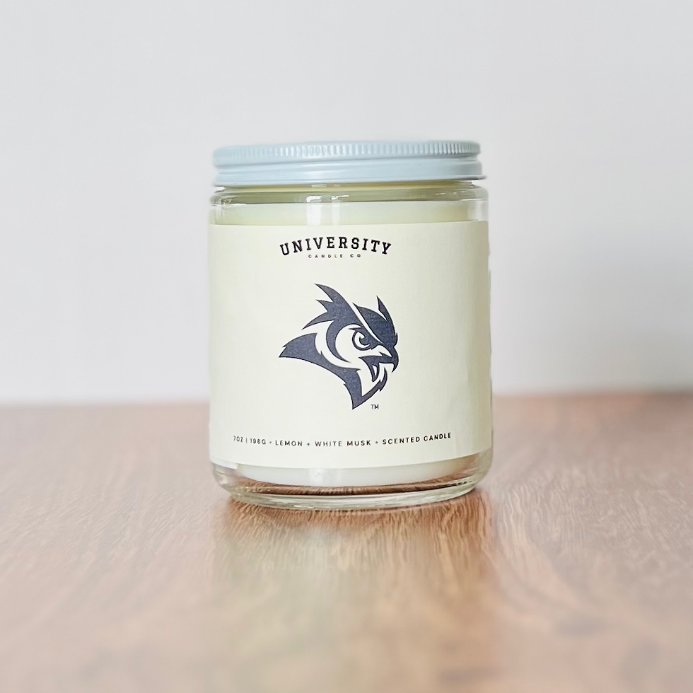 University Candle Co. candle with owl logo on wooden table.