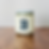 Jar candle with 'UNIVERSITY B' label, sitting on wooden surface.