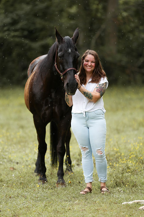 black horse with a white woman standing next to it