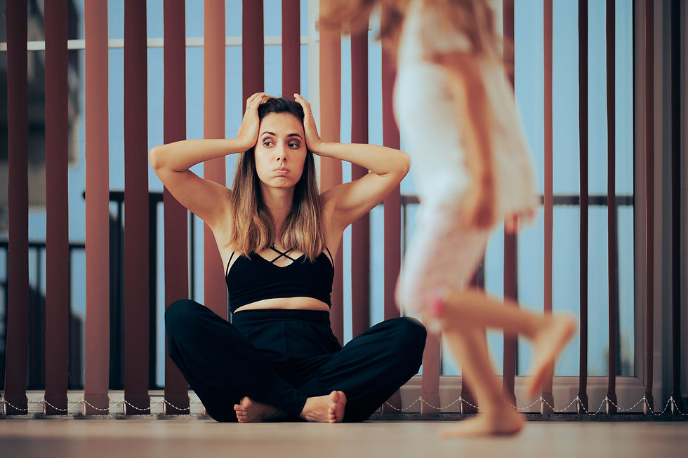 Woman in black sits cross-legged, holding her head in frustration. Child in motion blurs past. Background of vertical blinds.