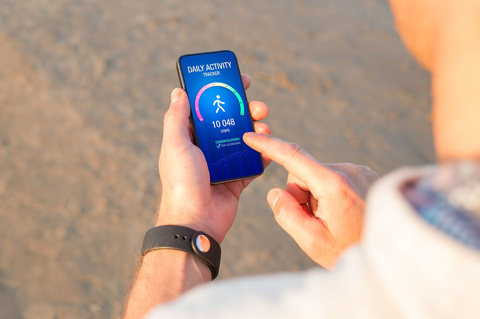 Hands using a phone step tracker on a sandy beach, showing 10,048 steps.