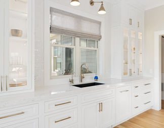 White kitchen cabinets and countertops with a window and sink detail.