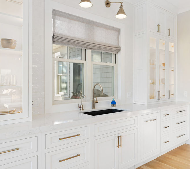 White kitchen with cabinets and sink, window view, and Manning Building Company.