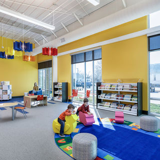 Children's library furniture with colorful lounge seating, low shelving, and playful accent pieces in a bright, modern public library