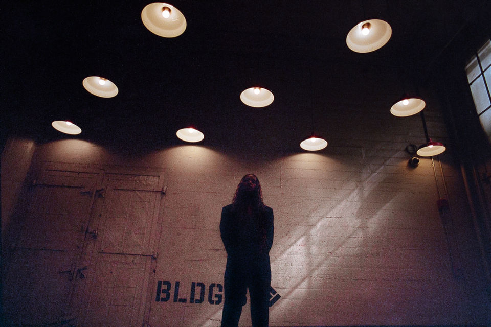 Black woman standing under several lights in a dimly lit building.