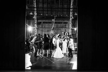 Bride surrounded by celebrating guests in the enchanted string-lit barn at Windmill Winery, dancing in this joyful community reception moment.