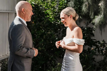 Bride's genuine laugh with tears during first look at Windmill Winery, an emotional reaction shot capturing joyful smiles in a verdant garden setting.