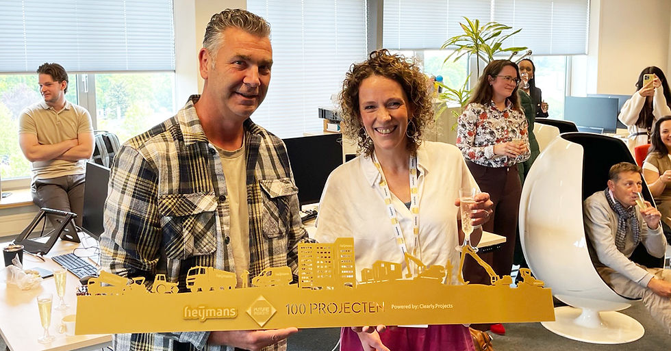 William Cornuijt (Heijmans) &amp; Mirella Hilgenkamp (Future Insight) pose proudly in an office space with a specially designed "100 projects" golden skyline award.