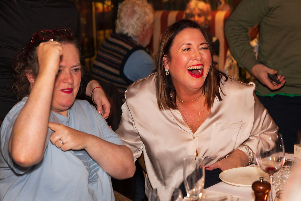 Two women laughing and celebrating at a dinner table