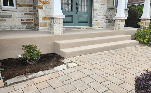 Escalier en béton décoratif avec colonnes blanches et pavés en pierre menant à une entrée résidentielle élégante à Joliette,