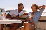 Man and woman enjoy wine on the back of a boat.