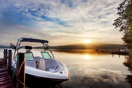Ski boat tied to a dock with the sunset behind it