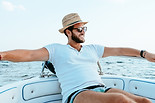 A man relaxes with arms stretched on the front of a boat.