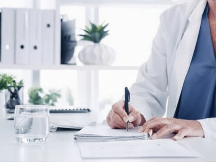 Femeie doctor in halat scriind intr-un carnetel