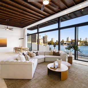 Open plan waterfront living space renovation at Isle of Capri Gold Coast by Barrile Building with modern coastal finishes