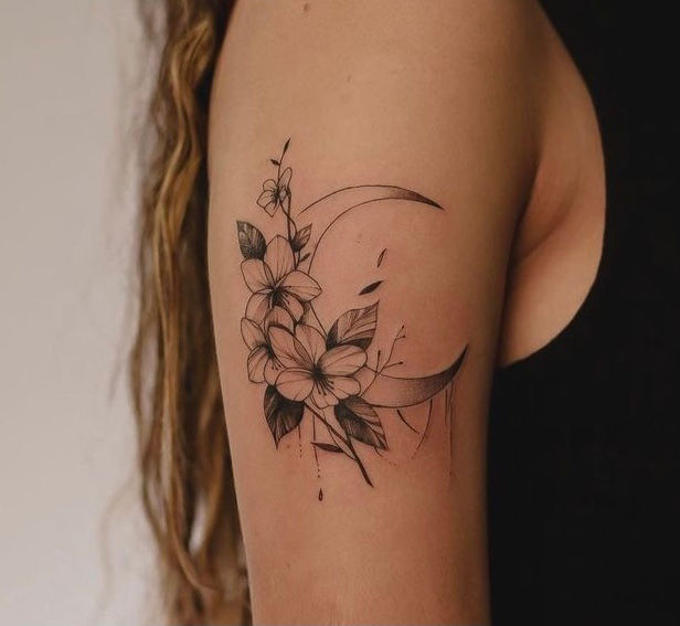thinly lined delicate linework flower and moon tattoo on wamand upper arm