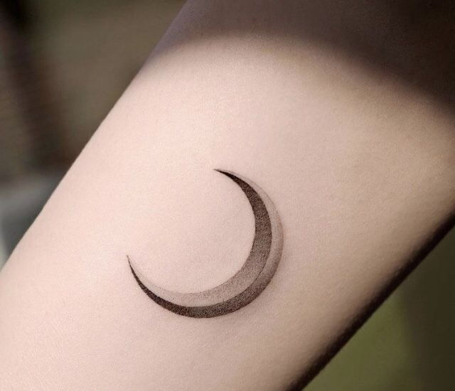 simple shaded soft black and grey moon crescent tattoo on female arm