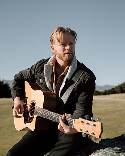 an acoustic guitar player in wanaka New Zealand, mountains in the background