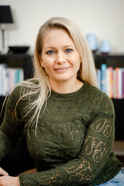 Erhvervsportræt af psykolog, der sidder i kontormiljø med bogreol i baggrunden. Branding billede.