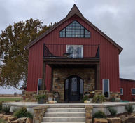 Modern barndominium with a decorative entrance made of stone.