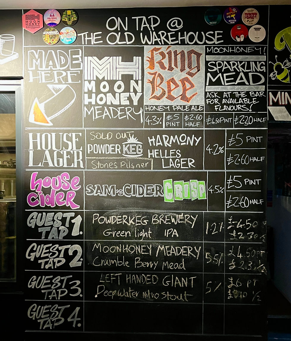 Photo shows the chalkboard menu of the taproom at The Old Warehouse in Kingsbridge, Devon. It shows a range of local beers and ciders, including their own Moonhoney Mead.