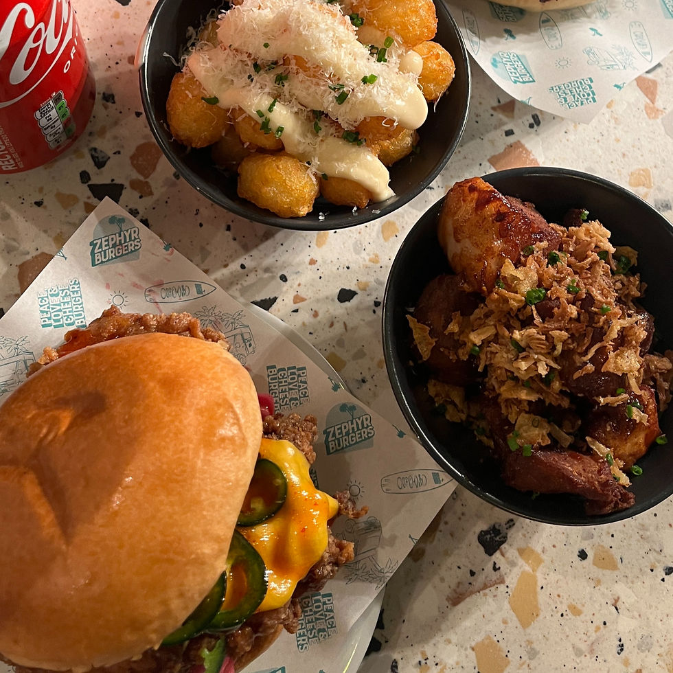 A bird's eye view of a burger and sides at Zephyr Burger, Plymouth including a chicken burger and loaded tater tots.