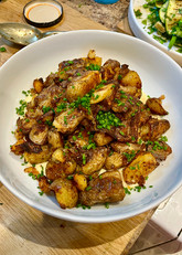 Crisp roast potatoes are plated with fresh chives and served on a layer of homemade mayonnaise.