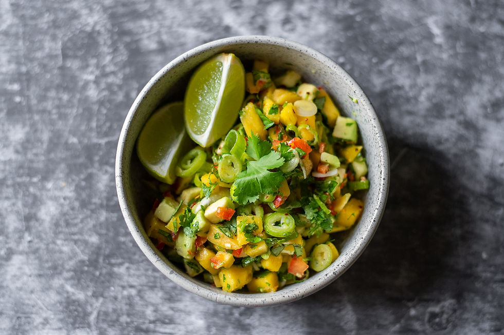 A bowl of chunky mango, avocado salsa is filled with vibrant yellow, red and green colours.