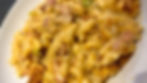 A cheesy sauces coats bacon lardons, spring onions and pasta