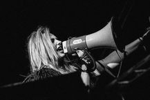 Karo Glazer singing into a megaphone on stage, immersive voice artist, composer and powerhouse vocalist performing live