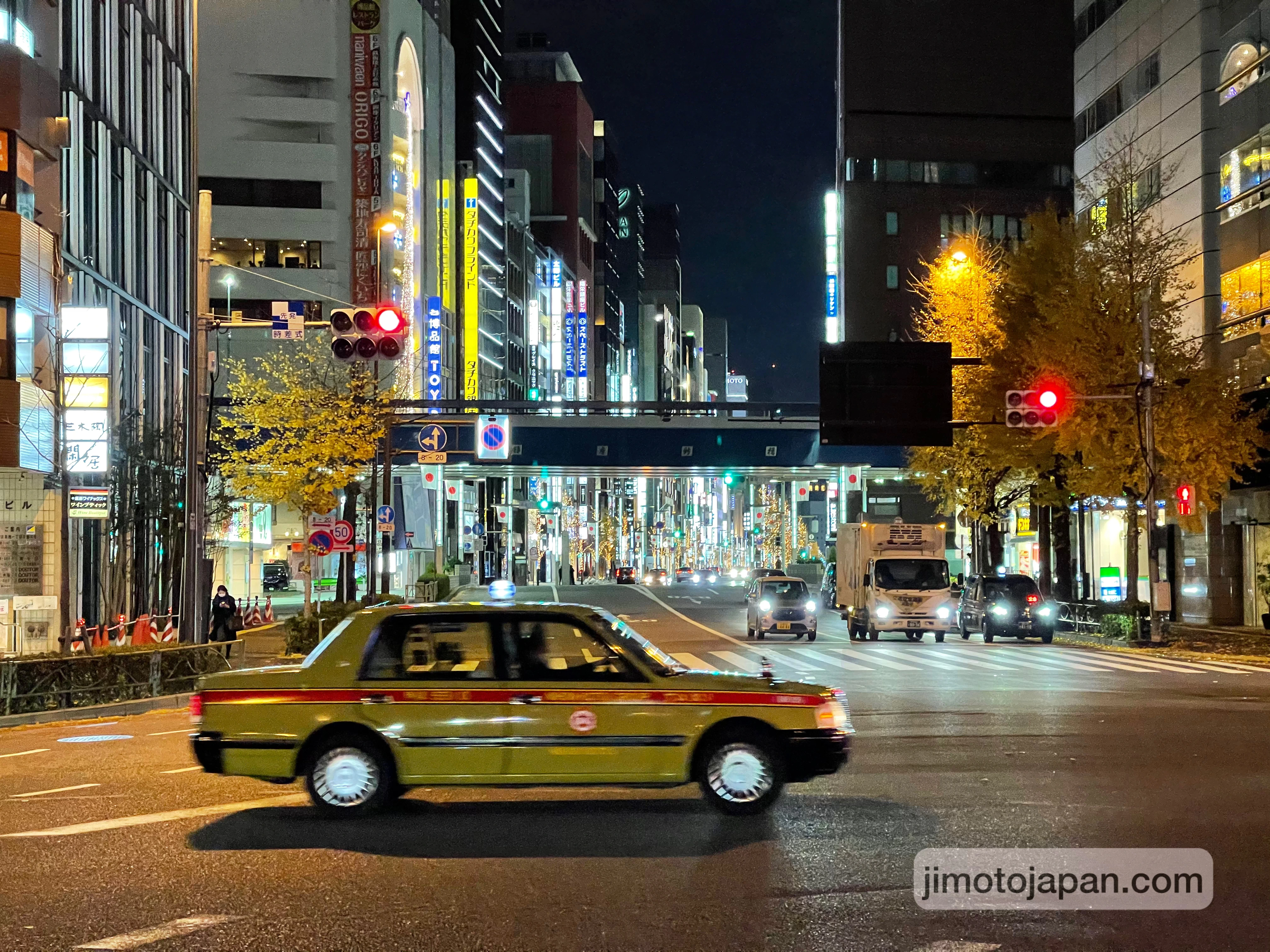 Busy city street in Japan at night with traffic and neon lights, showing a modern area where cash and credit cards are commonly used