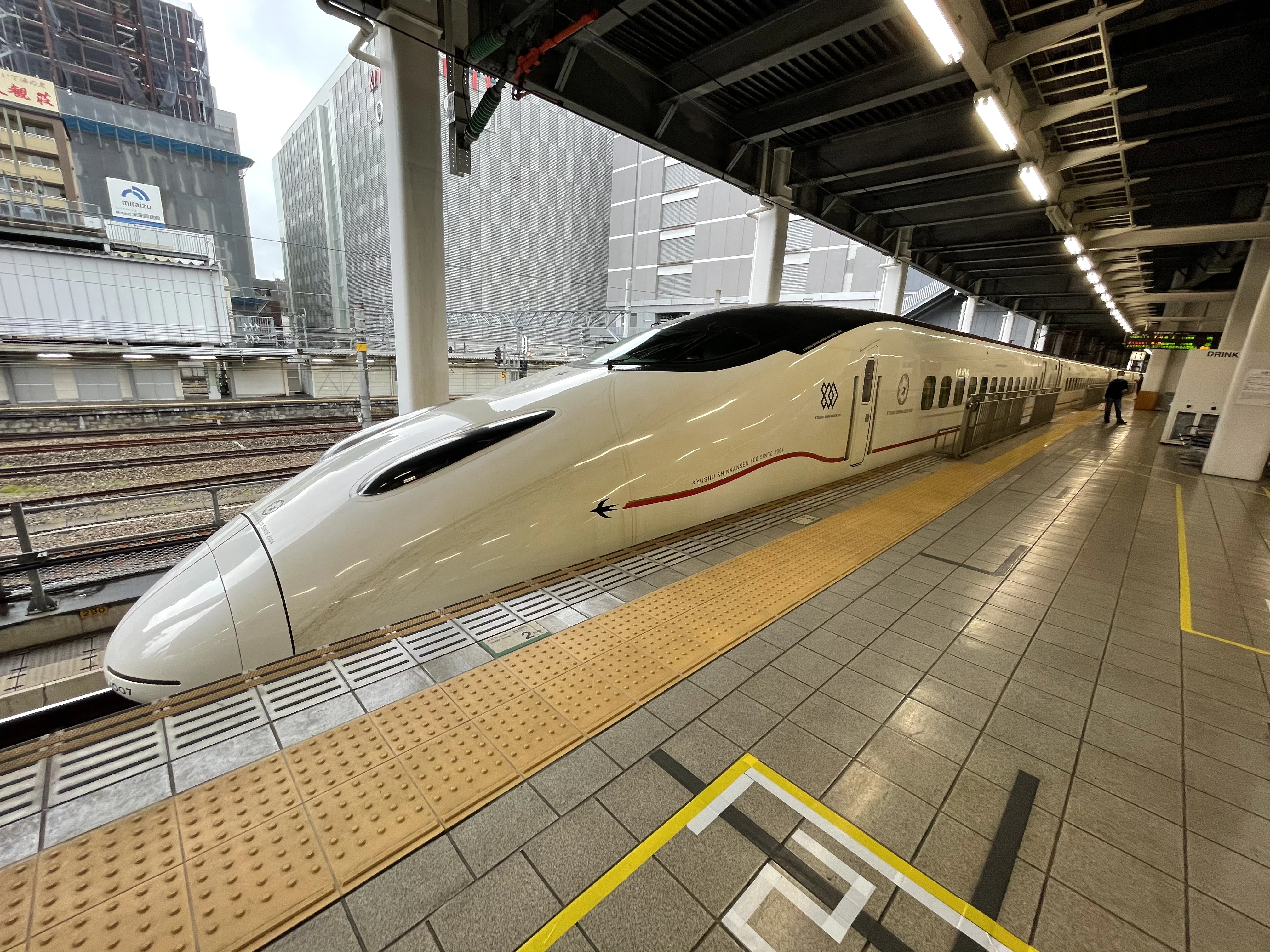 Shinkansen bullet train in Japan at a station platform, representing high-speed transportation with higher travel costs