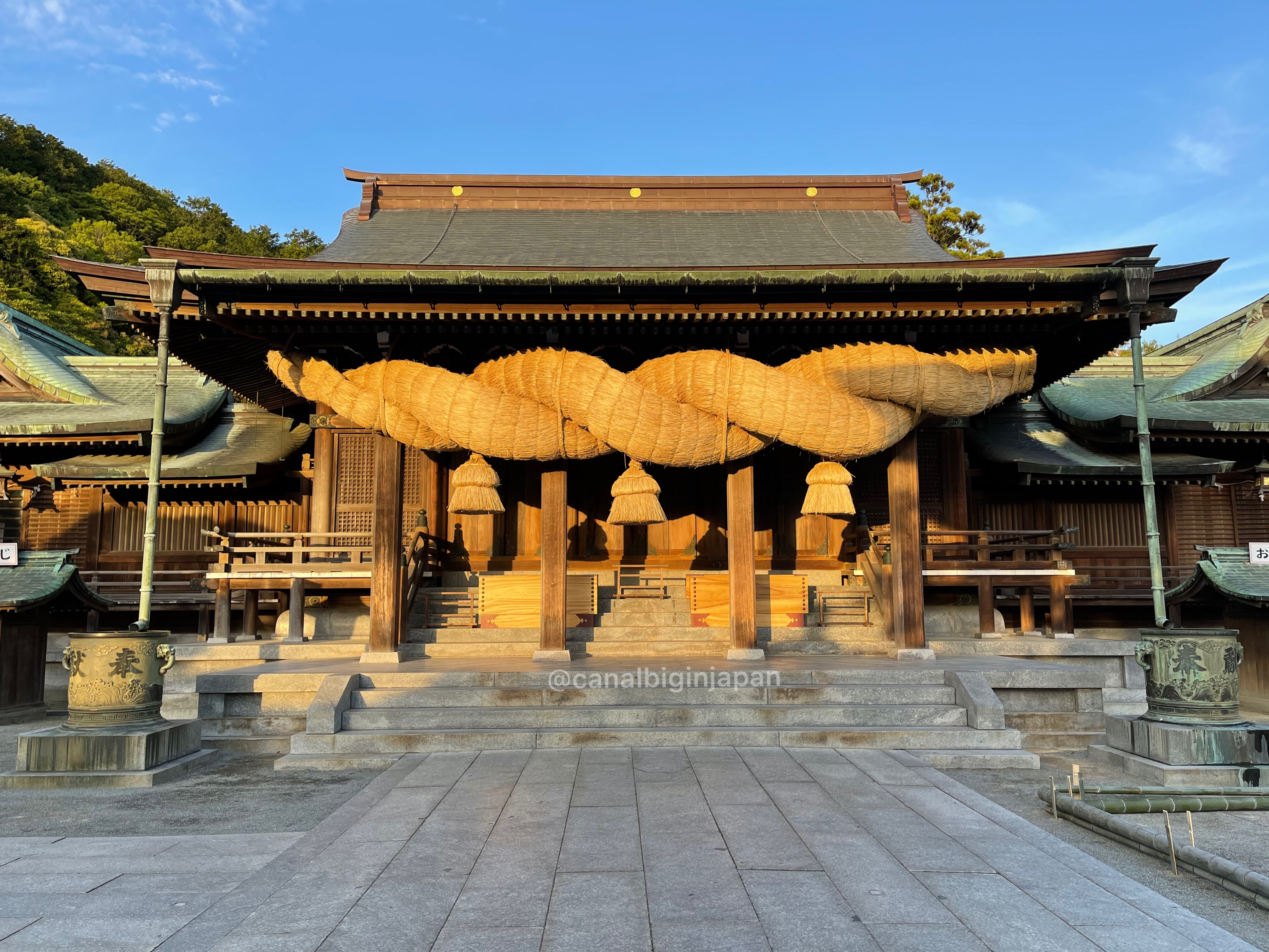 People visiting a Japanese shrine with lanterns and donation areas, showing traditional attractions where cash and coins are commonly used