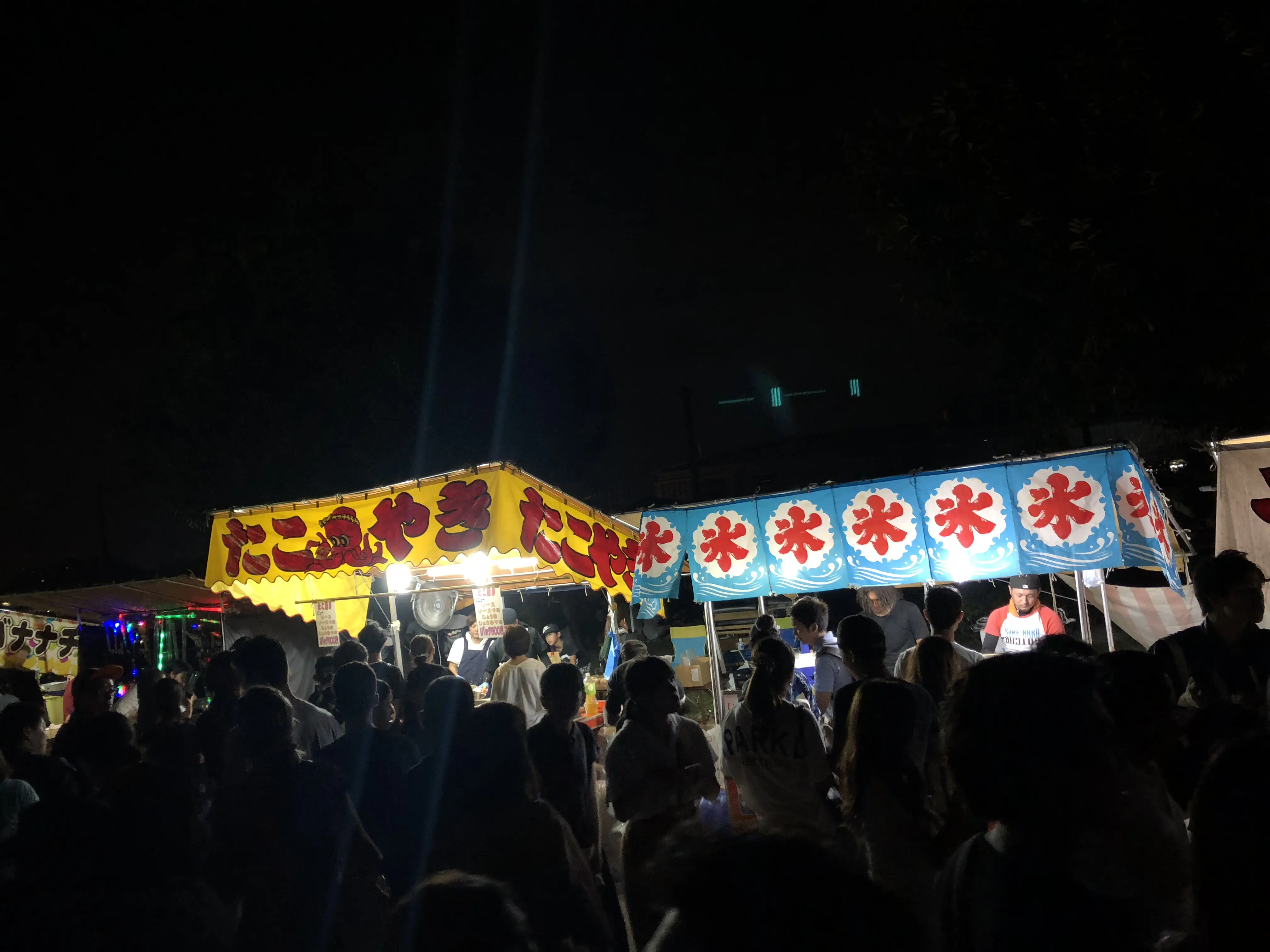 Night summer festival in Japan with crowded street food stalls and illuminated yatai.