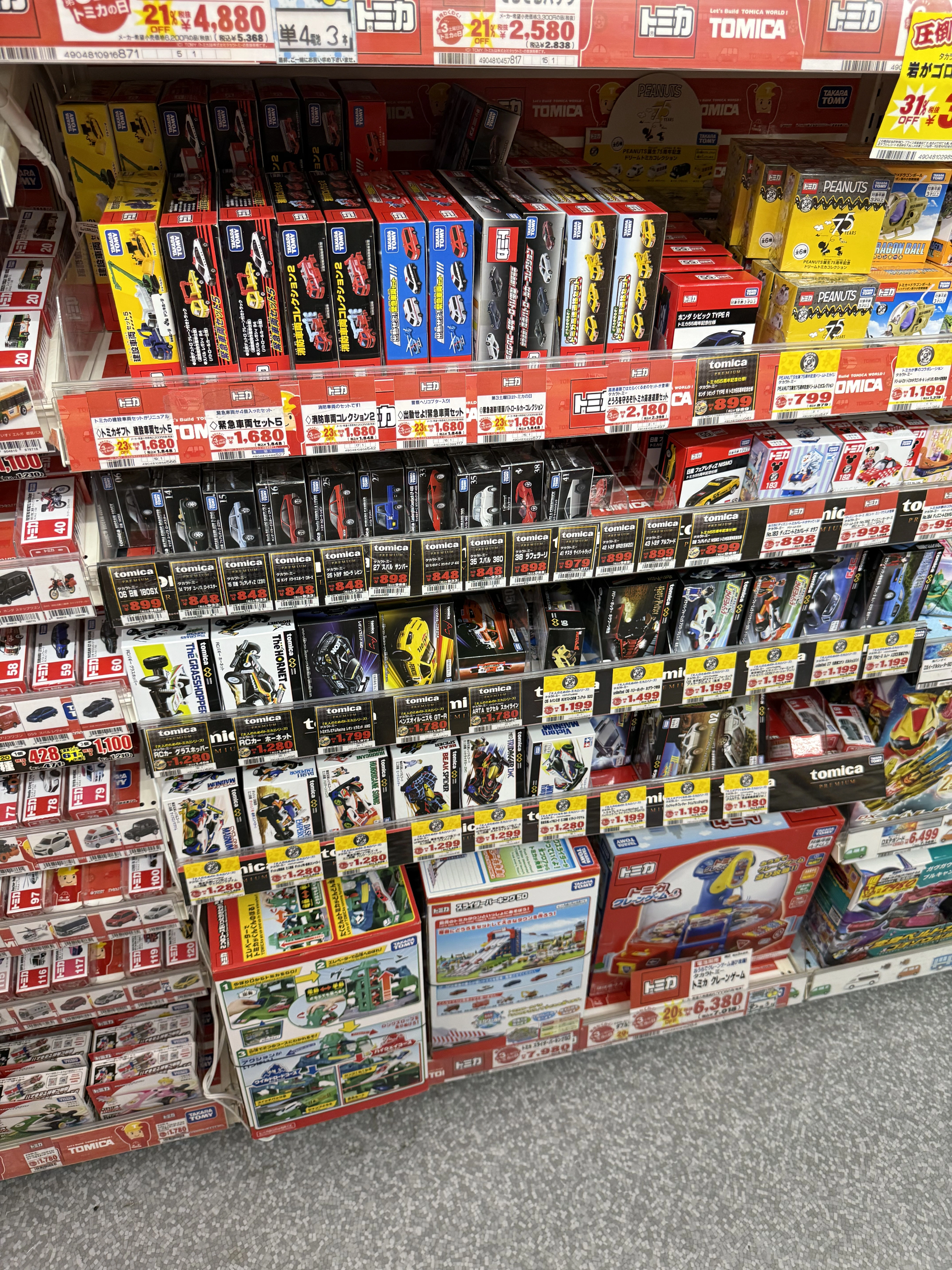 Tomica toy cars displayed on shelves in a Japanese store, showing popular collectible souvenirs often available tax free for tourists