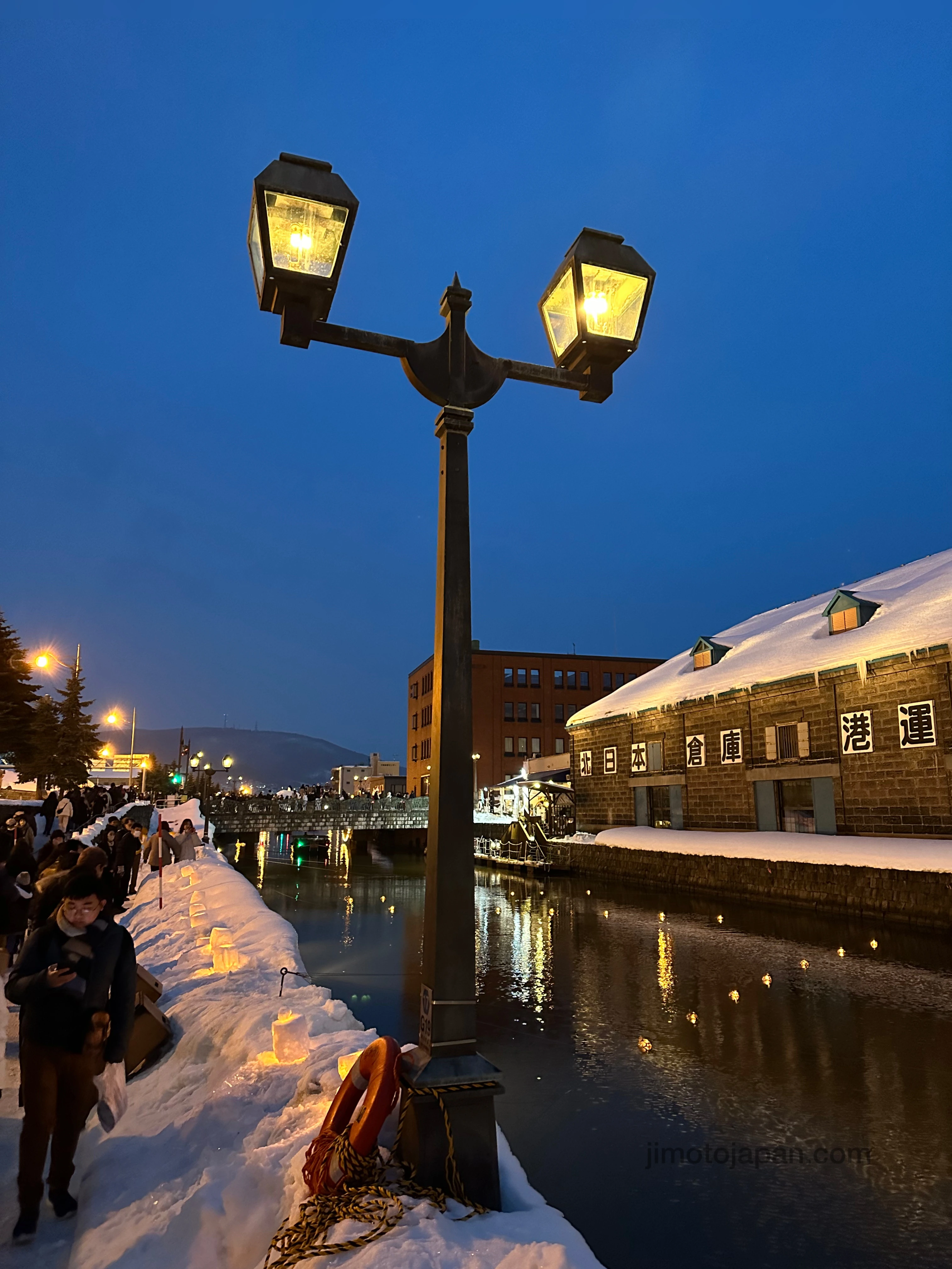 Winter evening in Otaru Canal with snow-covered streets and illuminated lanterns.