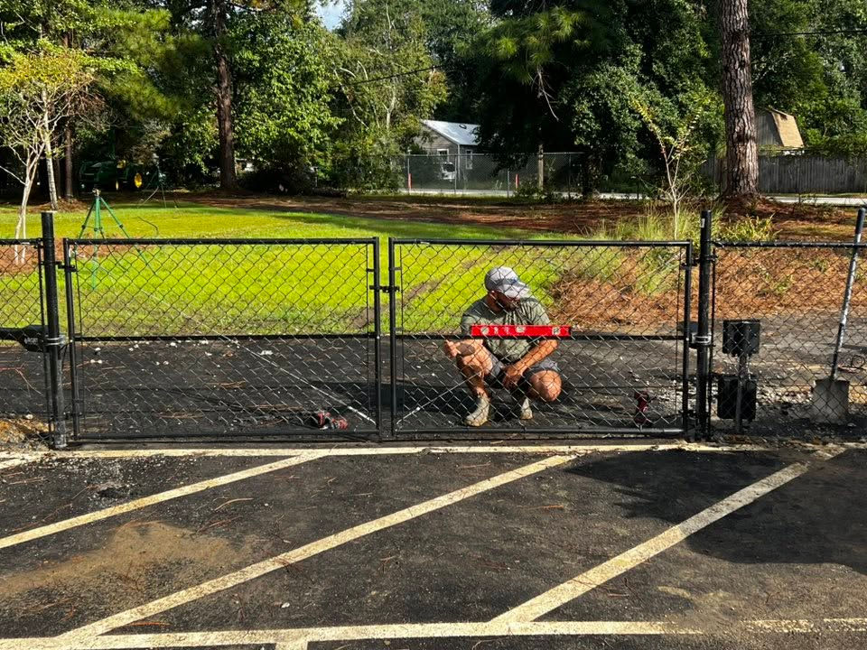 Black chain-link double swing gate being leveled at a parking lot