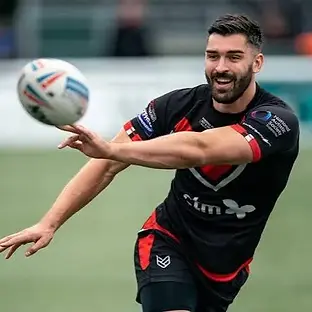 A professional rugby player passing a rugby ball looking committed and focused.