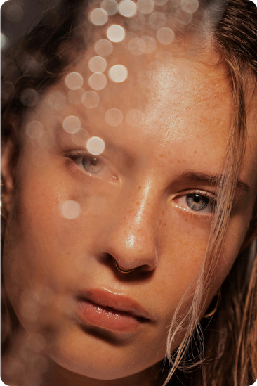 Close-up of a young woman's face with light bokeh overlays.