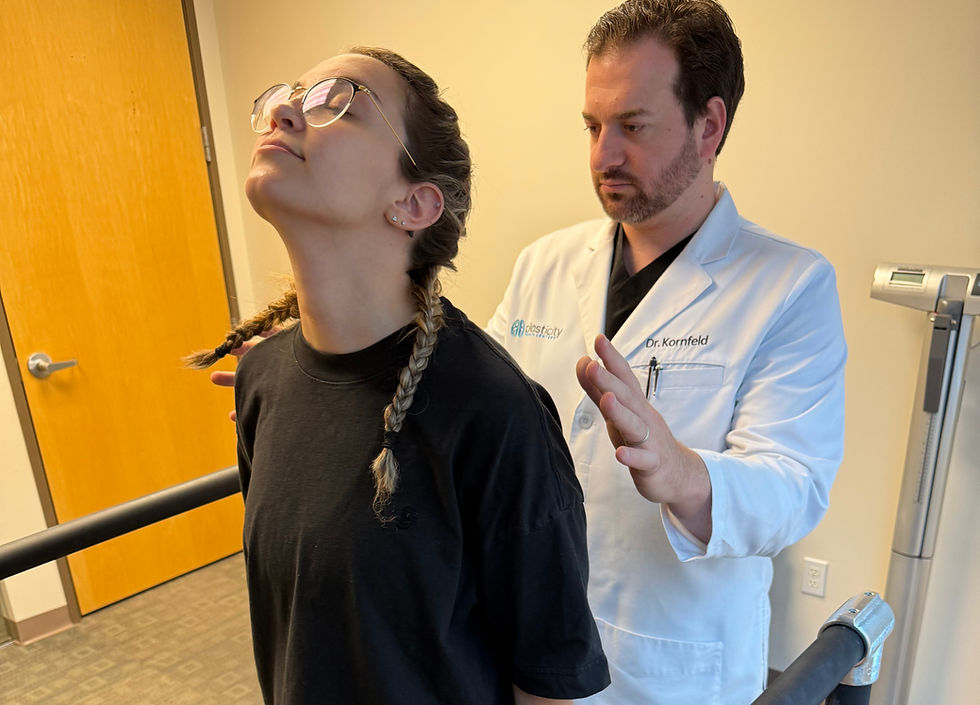 Dr. Kornfeld supporting a patient in a balance evaluation while standing with eyes closed and head tilted upward