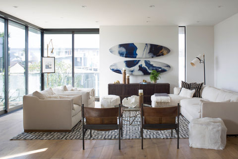 Modern living room with white sofas, surfboards, and wooden chairs KLI New