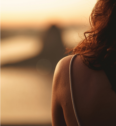 Woman with wavy hair looking at a beach sunset