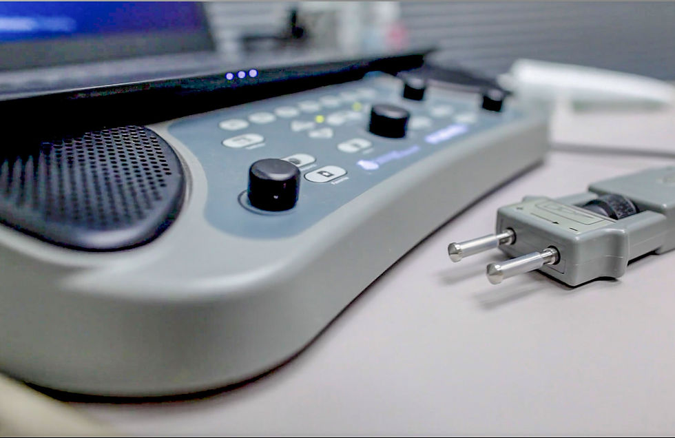 RPSS - Close-up of a gray hearing test device with control knobs on a table. A connected probe lies beside it. Soft focus on background.