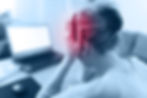 Back view of woman holding her head in pain while wearing headphones near a blurred laptop, blue-red tinted.