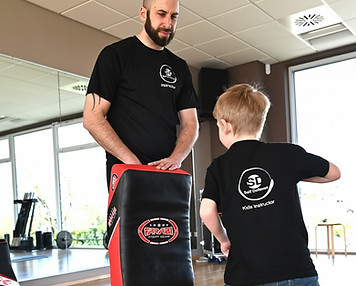 Trainer macht mit Grundschüler zusammen schlagübungen